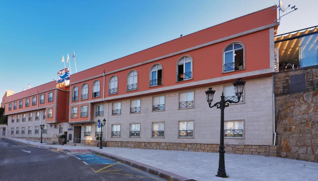 un edificio rojo y blanco con una luz de la calle delante en Hotel Apartamentos Dabarca, en Pontevedra