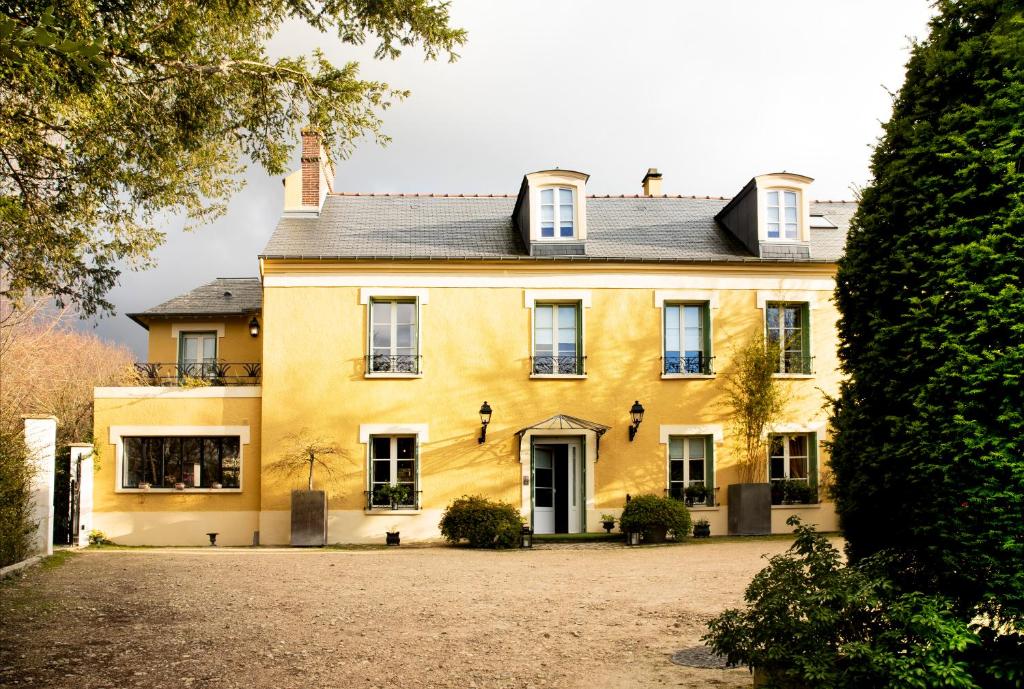 een groot geel huis met een grote tuin bij Le Clos de Villeroy in Mennecy