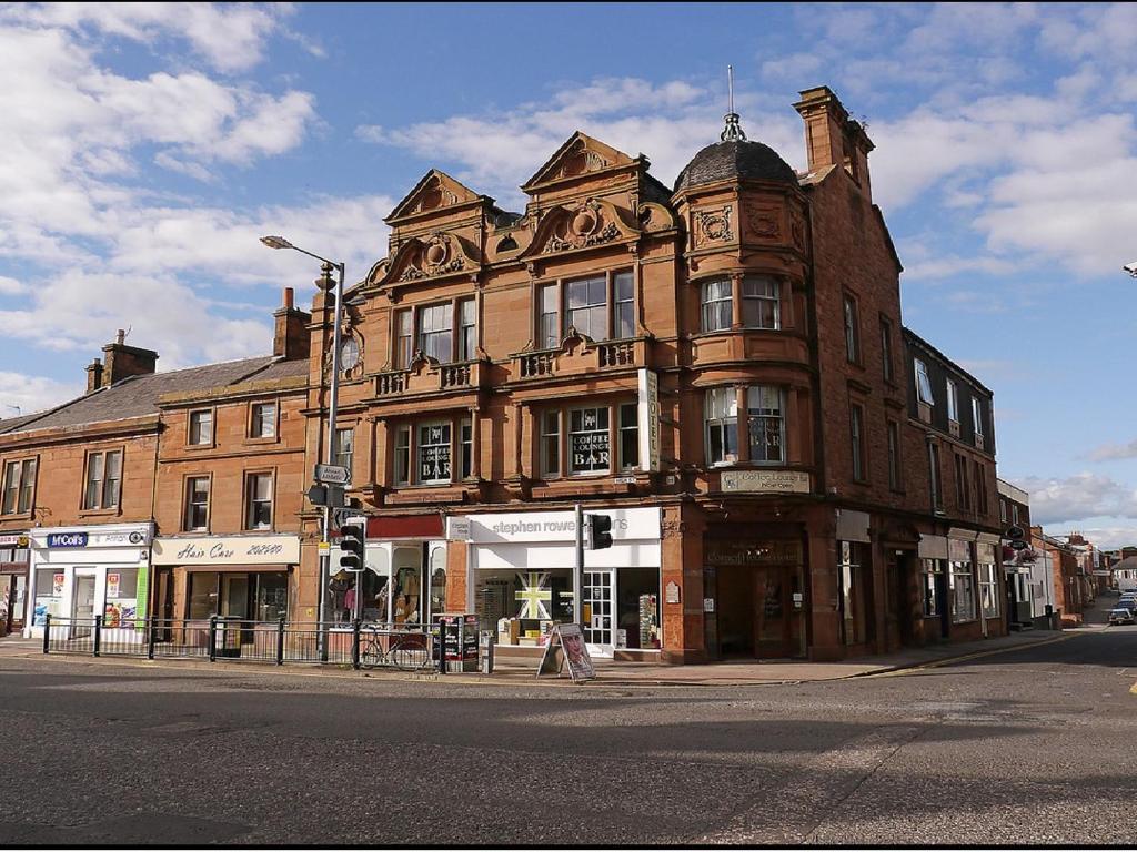 un gran edificio de ladrillo en la esquina de una calle en The Corner House Hotel en Annan