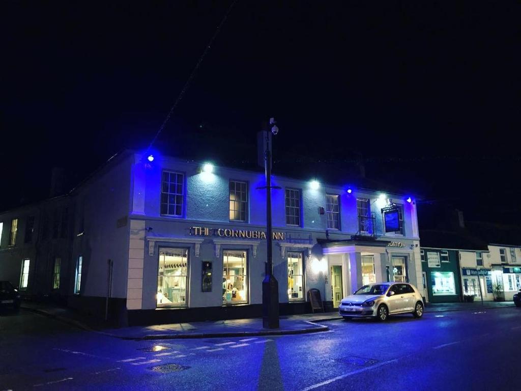 un edificio con luces azules en una calle por la noche en The Cornubia Inn, en Hayle