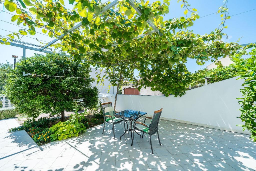 un patio con mesa y sillas bajo un árbol en Villa Marija Adriatic en Mlini