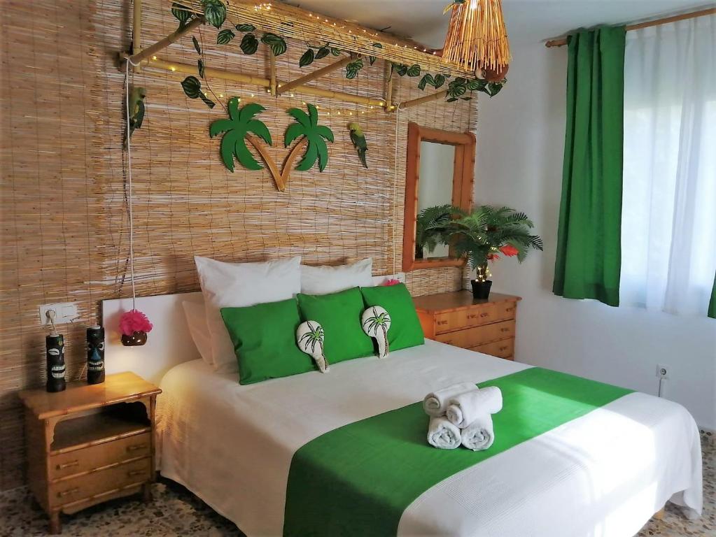 Wonder Rooms Nerja Guest House في نيرخا: غرفة نوم بسرير اخضر وبيض مع منشفتين