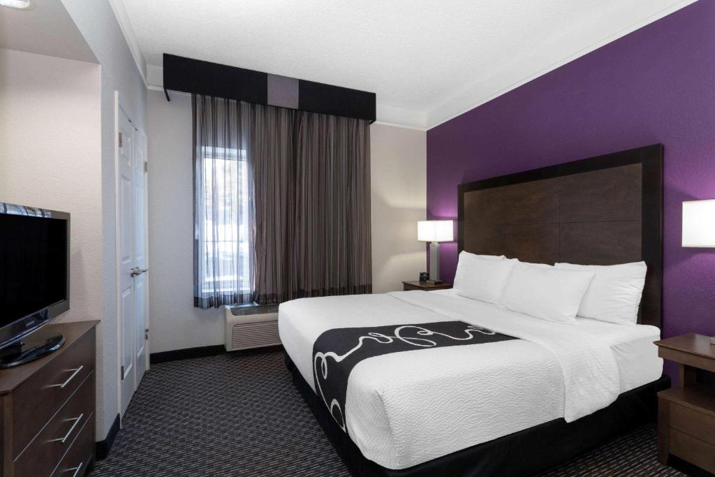 Cette chambre d'hôtel dispose d'un grand lit et de murs violets. dans l'établissement La Quinta by Wyndham Denver Boulder - Louisville, à Louisville