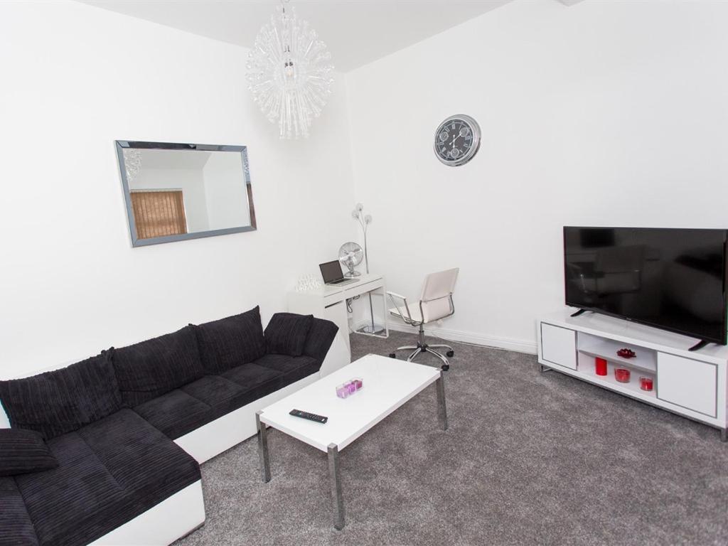 Luxurious Serviced Apartments في ليدز: غرفة معيشة مع أريكة سوداء وتلفزيون
