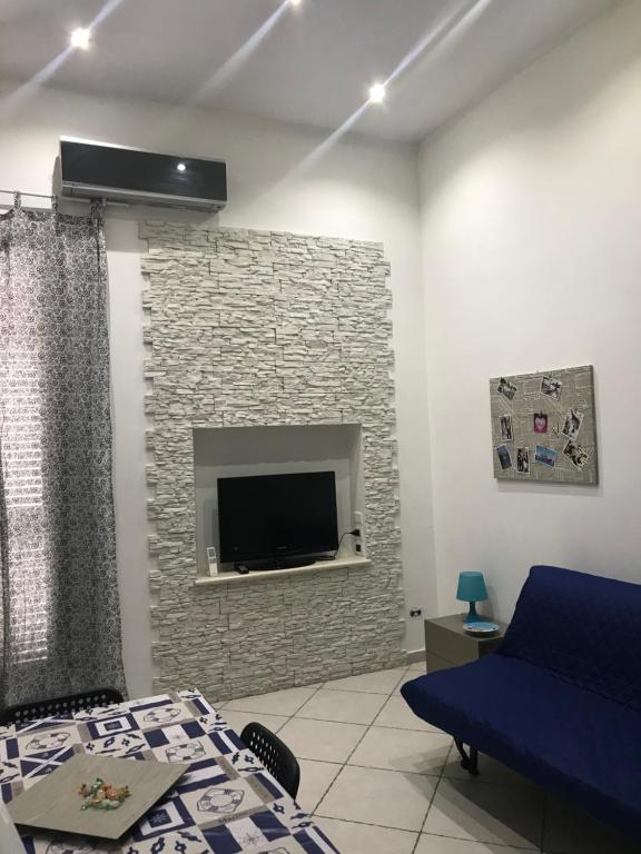uma sala de estar com televisão numa parede de tijolos em Salinis Apartments em Margherita di Savoia