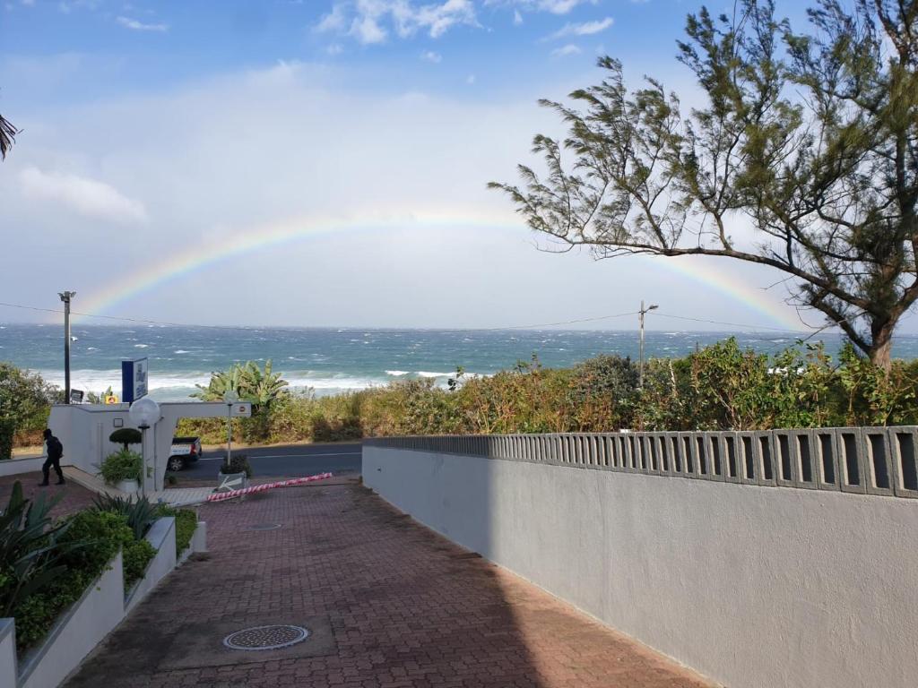 a rainbow in the sky over the ocean with a sidewalk at La Mercy Beach Hotel in La Mercy