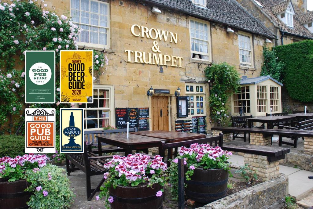 un restaurant avec des tables et des fleurs devant lui dans l'établissement Crown and Trumpet Inn, à Broadway