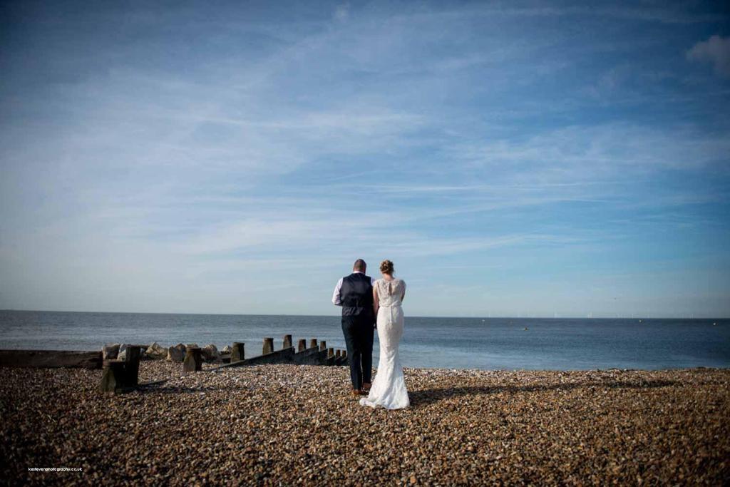 a bride and groom standing on the beach at The Marine in Whitstable