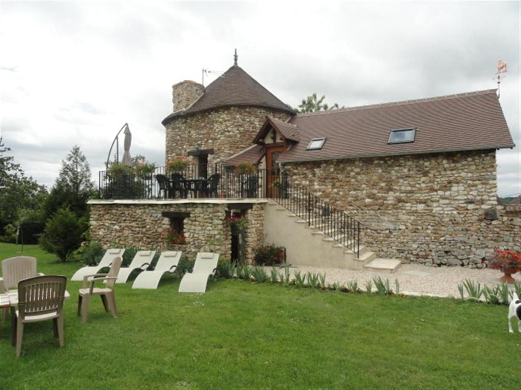 um edifício de pedra com um grupo de cadeiras num quintal em Les Grandes Vignes em Saint-Étienne-sous-Bailleul