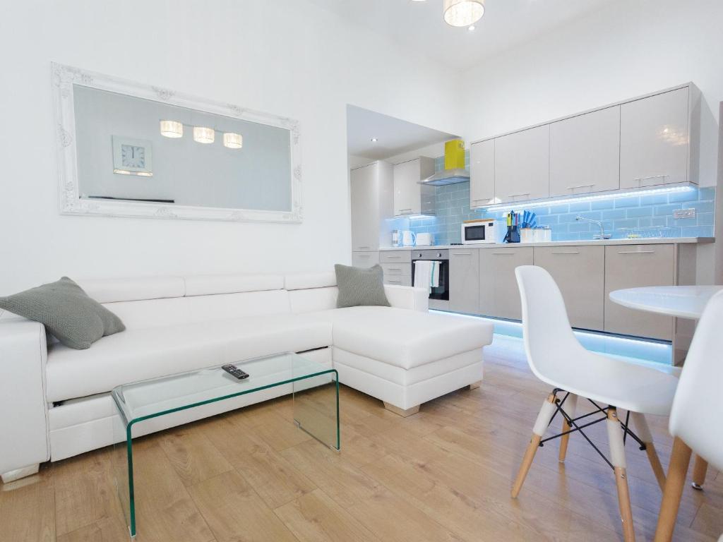 a white living room with a white couch and a table at Live in Leeds Greenhill Bungalows in Leeds