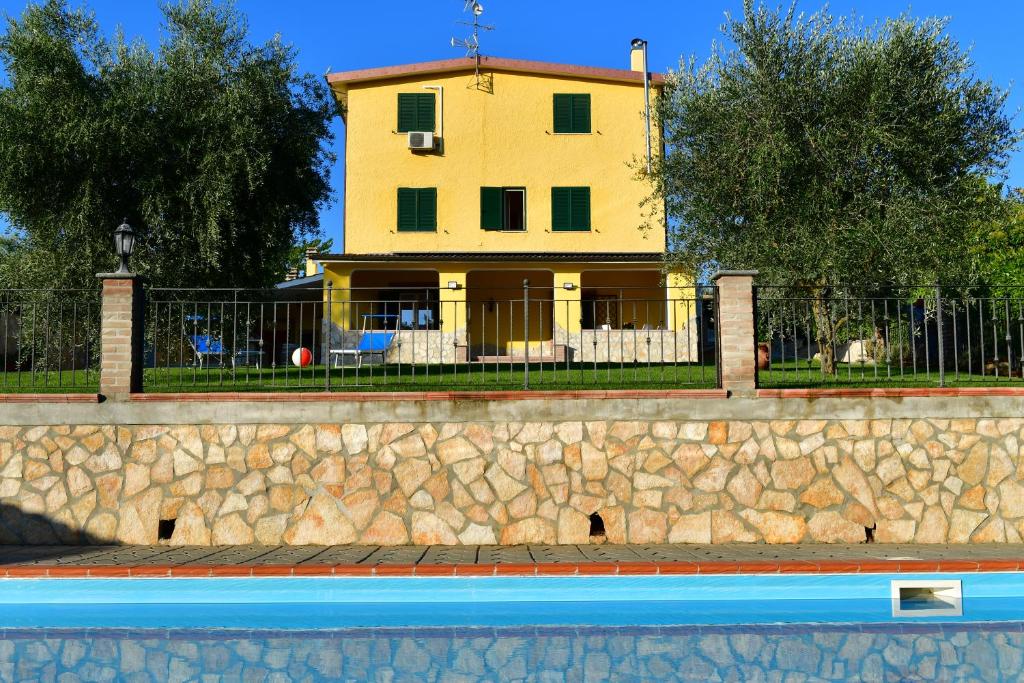 een geel huis achter een stenen muur met een zwembad bij B&B Roman Country Villa in Zagarolo