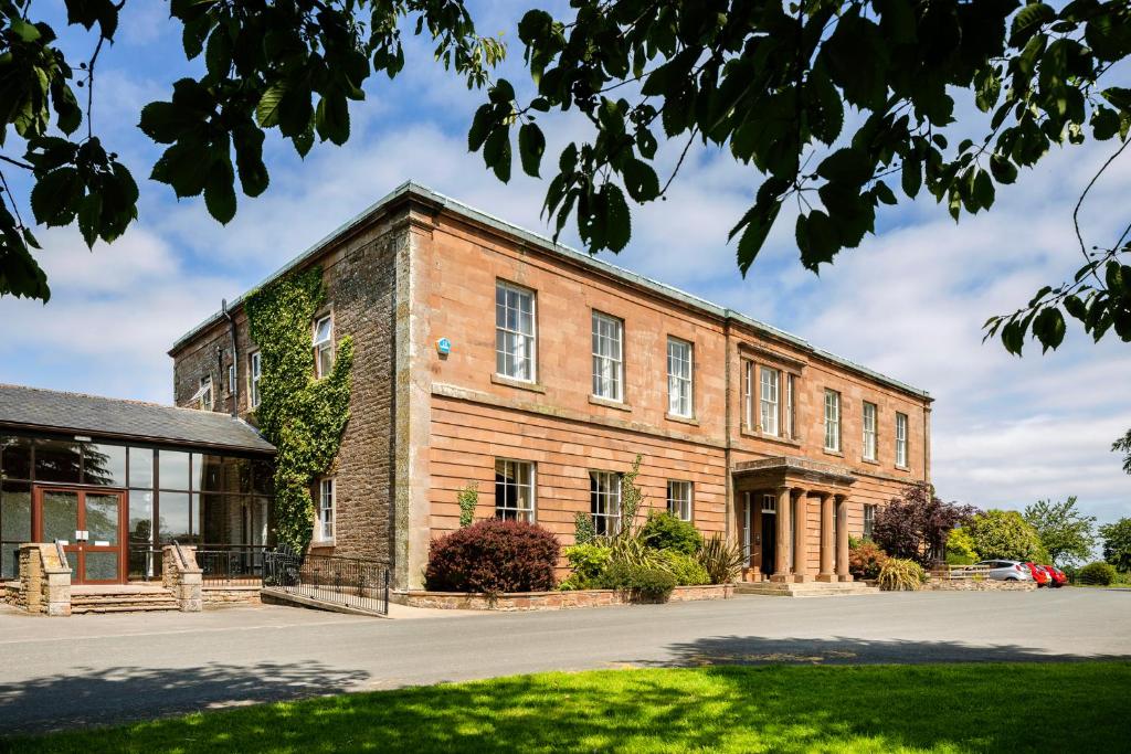 an old brick building with ivy on it at The Greenhill Hotel in Wigton