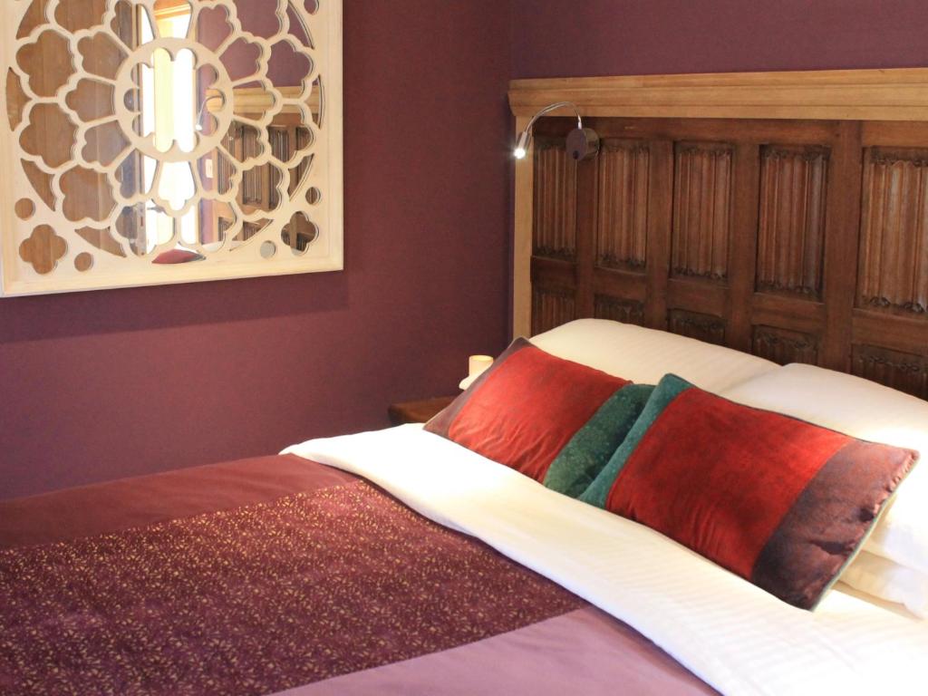 a bedroom with a bed with colorful pillows on it at The Lodge at Hemingford Grey House in Hemingford Grey