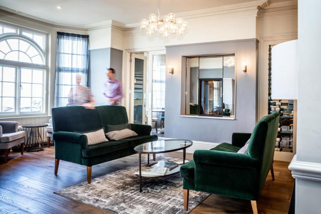 a living room with green furniture and a chandelier at The Marine in Whitstable