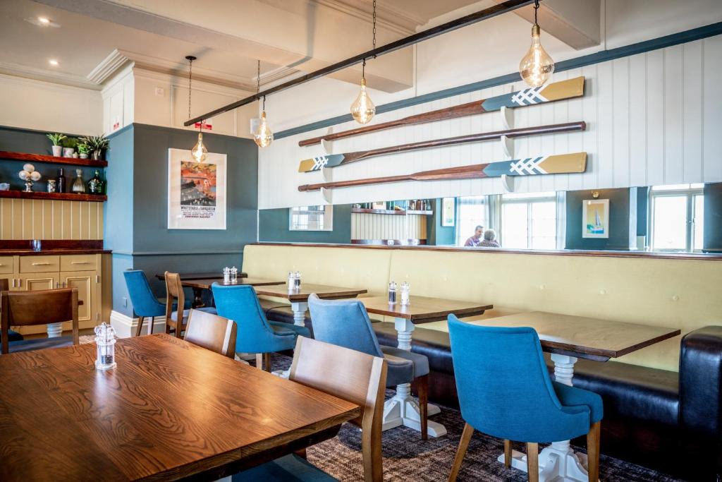 a restaurant with wooden tables and blue chairs at The Marine in Whitstable