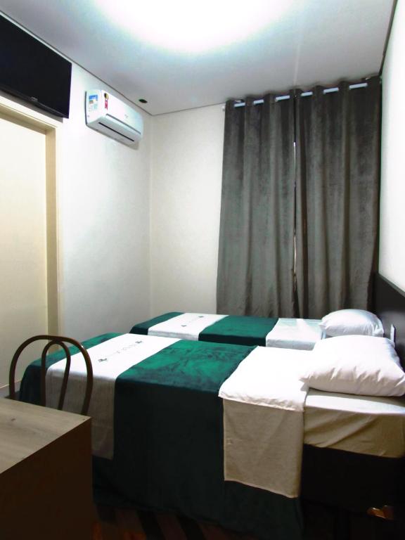 ein Hotelzimmer mit zwei Betten und einem Fenster in der Unterkunft Hotel Minho - Ótima Escolha Próximo à 25 de Março, Brás, Bom Retiro e Metrô - Café da Manhã Incluso - Estacionamento em Frente in São Paulo