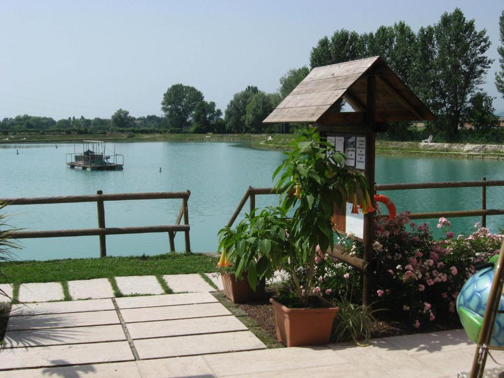 a gazebo next to a lake with a boat at Laghetto ai Portici in Pastrengo