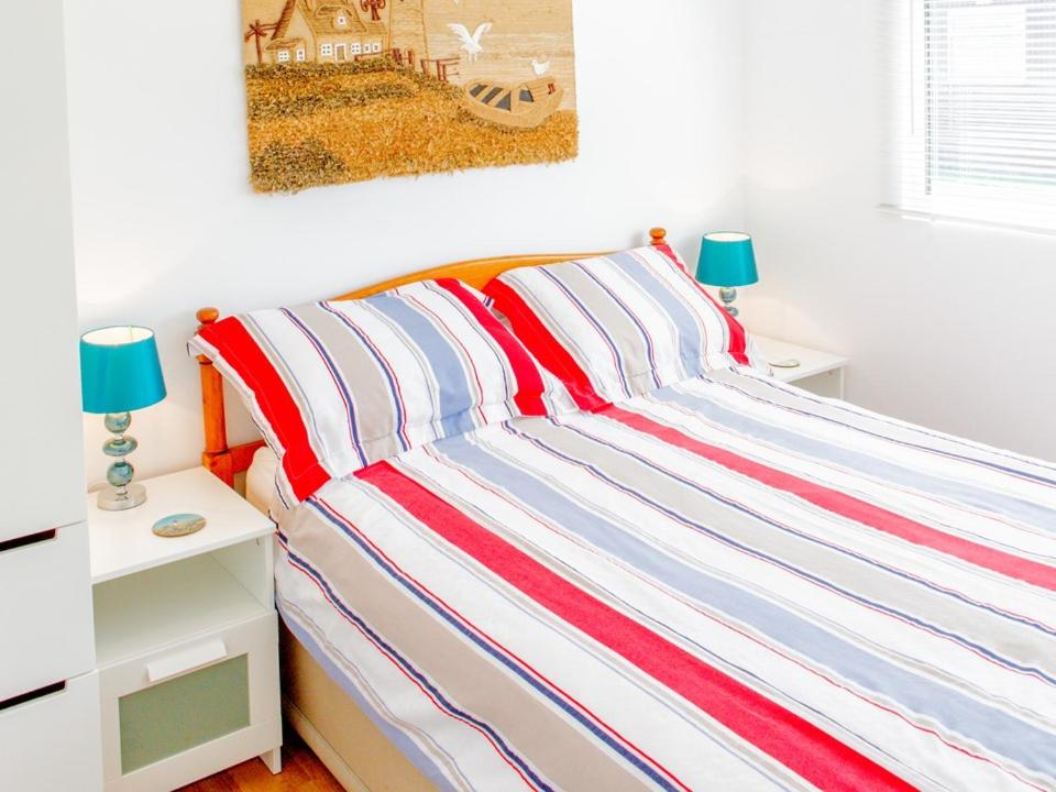 un letto con copriletto a righe in una camera da letto di Hi-De-Hi Chalet 111 a Dartmouth