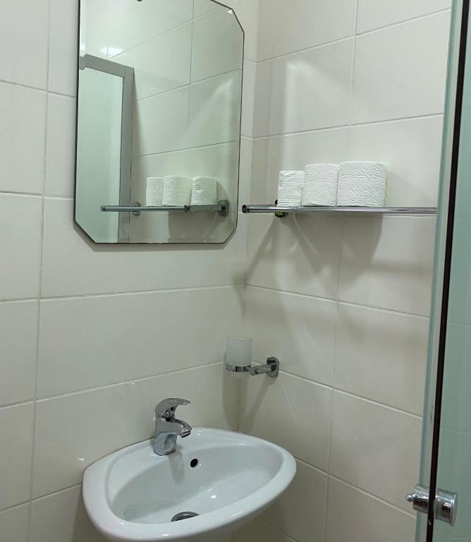 a white bathroom with a sink and a mirror at Apartments Boss in Budva