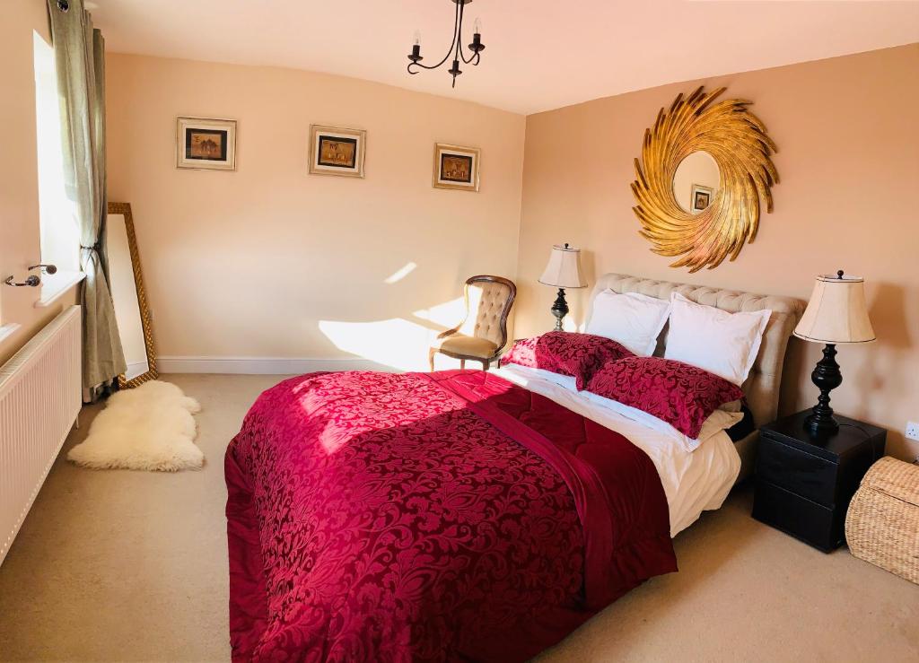 a bedroom with a bed with a red comforter and a chair at Holiday Home Epworth in Epworth