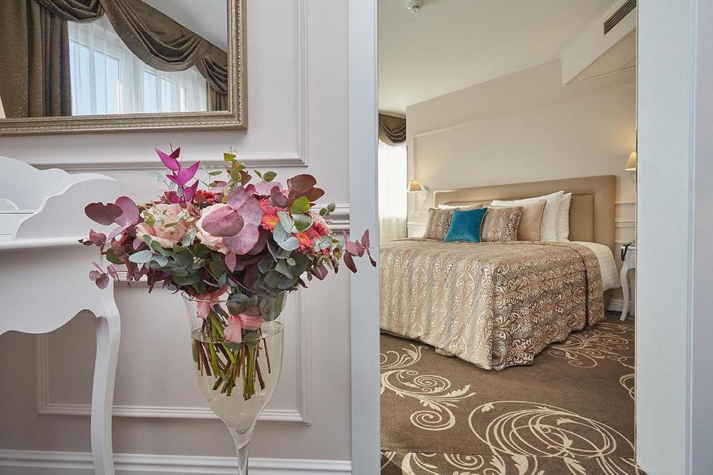 a hotel room with a vase of flowers in a bedroom at Don Giovanni Hotel Prague - Great Hotels of The World in Prague