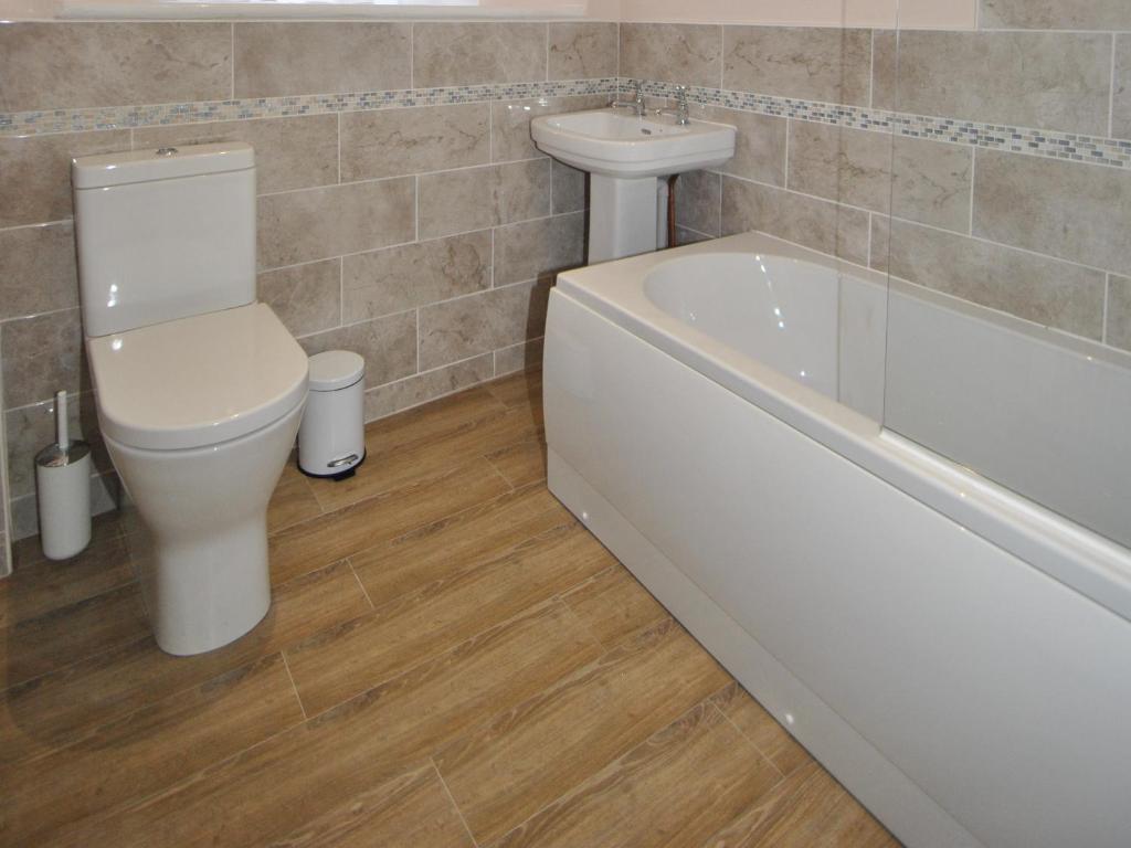 a bathroom with a toilet and a sink and a bath tub at The Hood Arms in Kilve