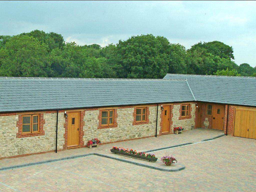 a building with orange doors and a courtyard at Hook Farm Cottages in Royal Wootton Bassett