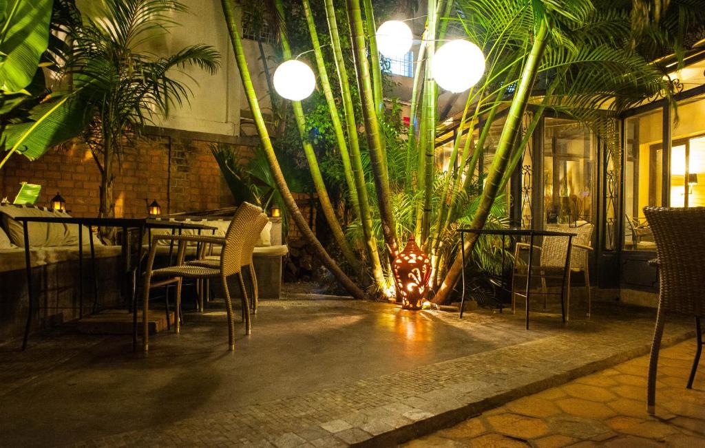 een restaurant met een tafel, stoelen en planten bij Hôtel Restaurant La Ribaudière in Antananarivo