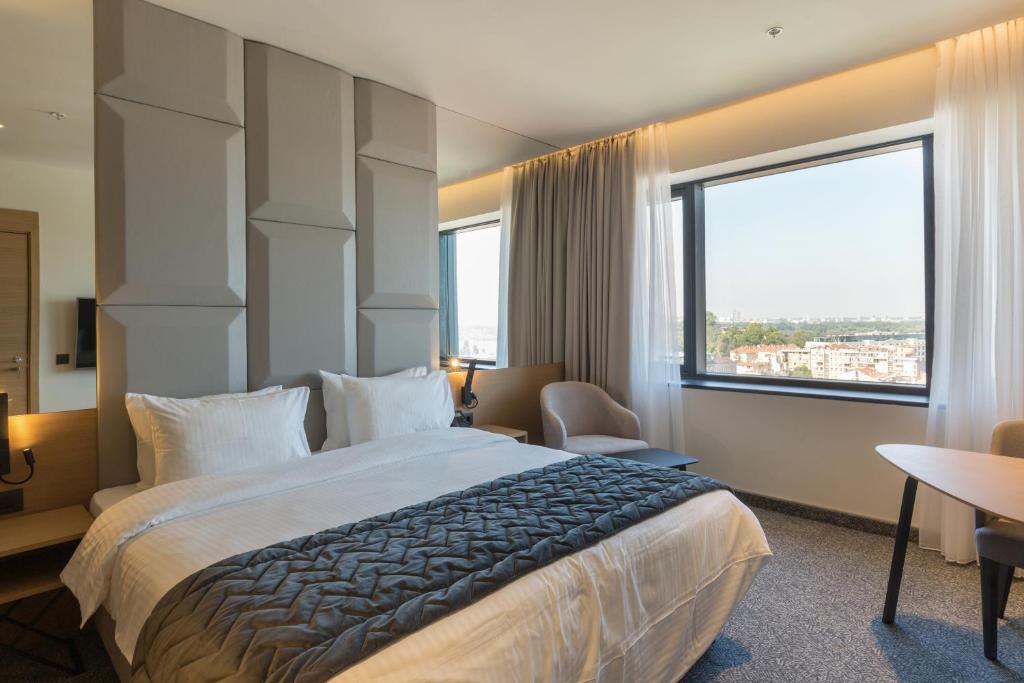 Habitación de hotel con cama grande y ventana grande. en Hotel Mona Plaza en Belgrado