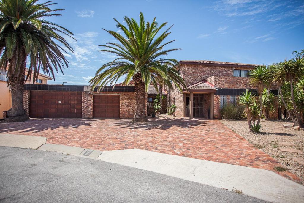 uma casa de tijolos com palmeiras e uma entrada em Bluewater Bay Vakhusi on 7 Joycelyn em Port Elizabeth