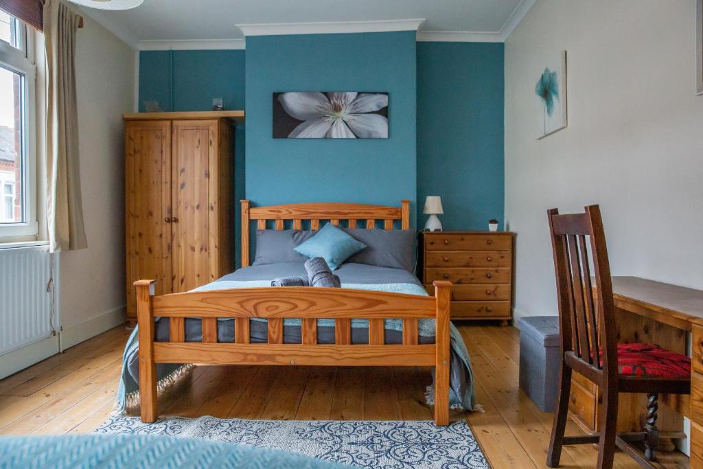 Schlafzimmer mit Holzbett und blauen Wänden in der Unterkunft I'm Your Host - Westcotes Stay in Leicester