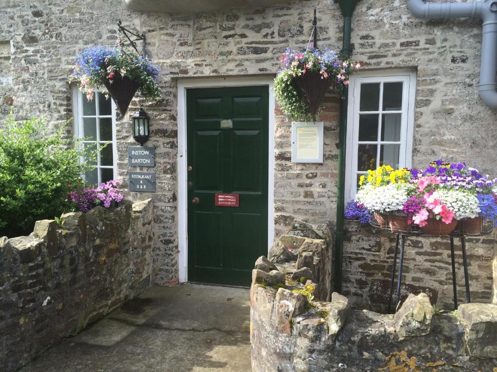 a green door on a stone house with flowers at Instow Barton in Instow