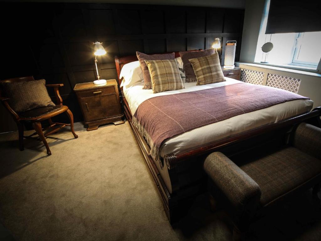 a bedroom with a bed and a chair and a lamp at The Plough Bicester in Bicester