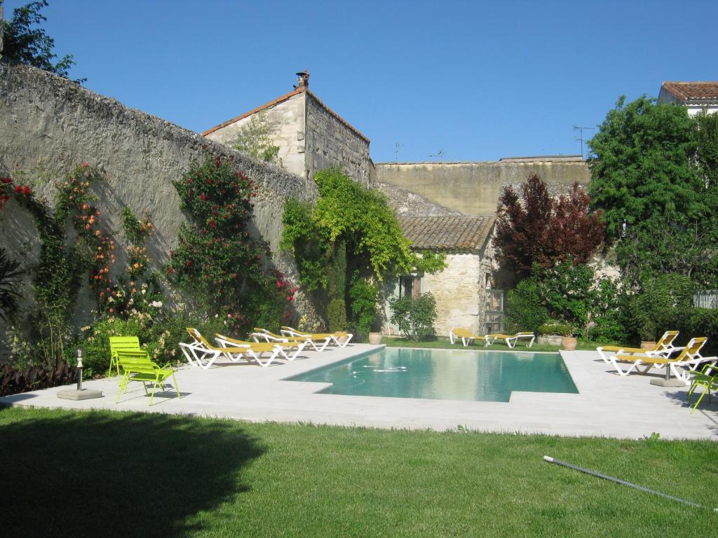 una piscina en un patio con sillas y una pared en Les Jardins De La Livrée, en Villeneuve-lès-Avignon