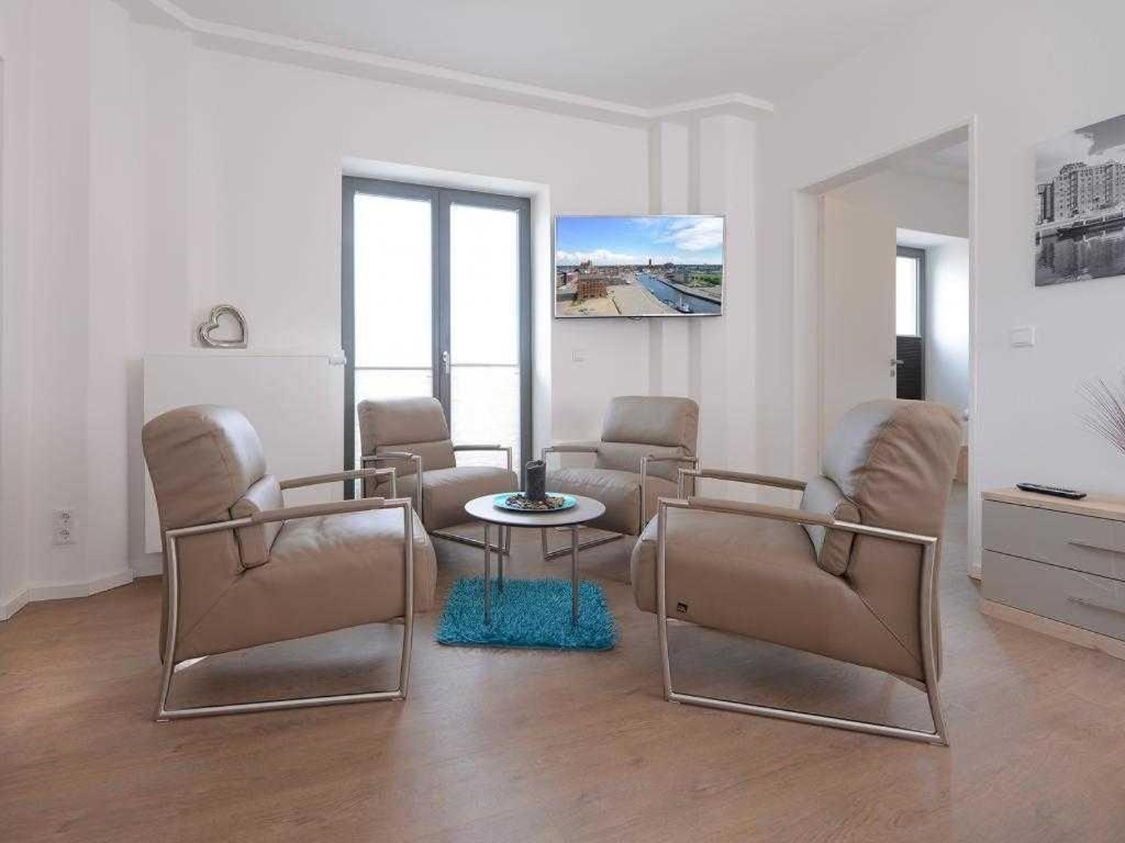 a living room with chairs and a table and a tv at Ohlerich Speicher App_ 05 in Wismar