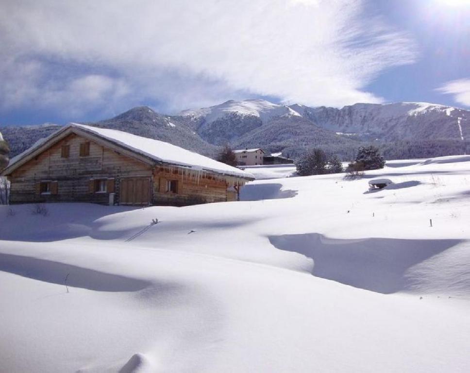 une cabane en rondins dans la neige avec des montagnes en arrière-plan dans l'établissement Ker Puigmal, à Saint-Pierre-dels-Forcats