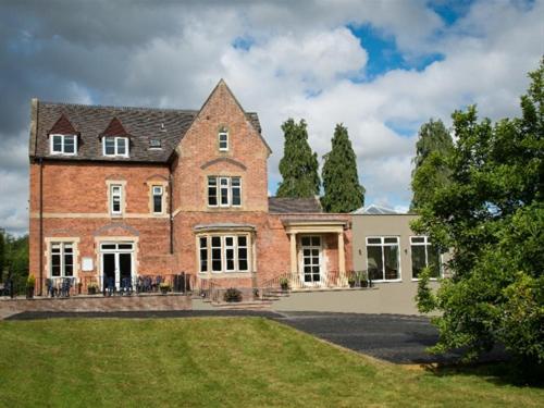 a large brick house with a lawn in front of it at The Cliffe at Dinham in Ludlow