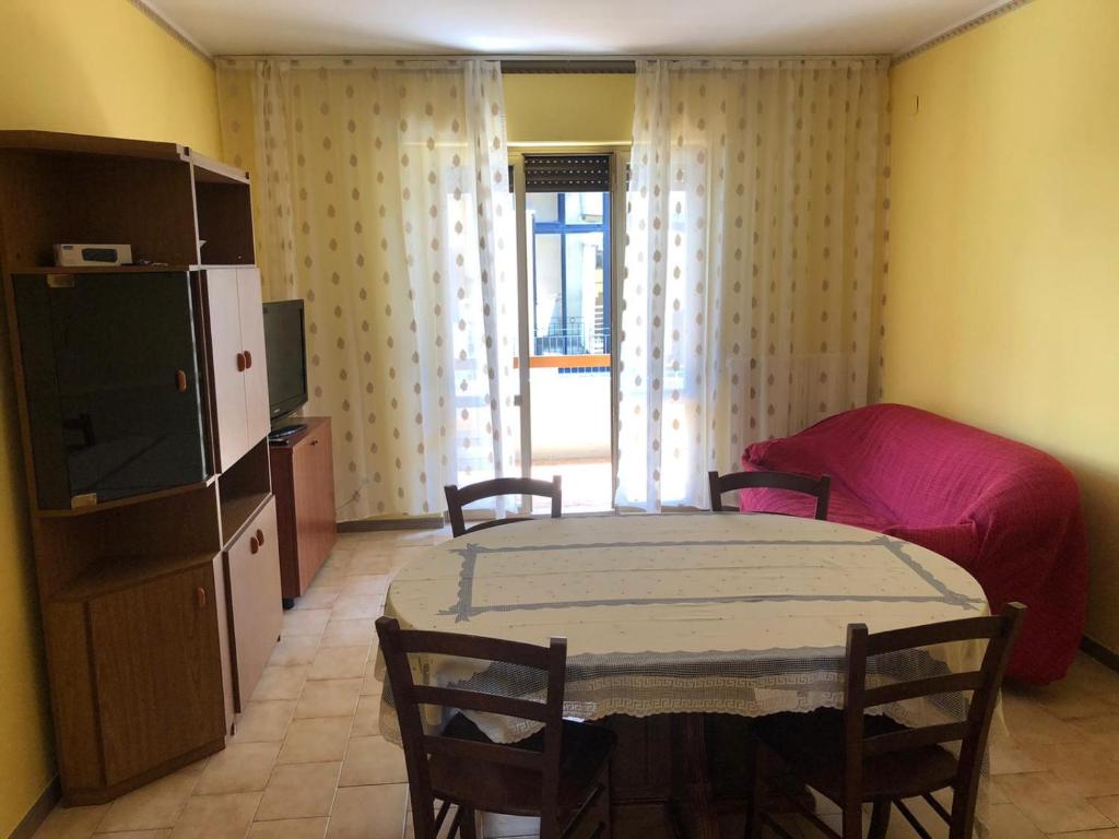 Appartamento Gemma في مارتينسيكورو: غرفة معيشة مع طاولة وأريكة وتلفزيون