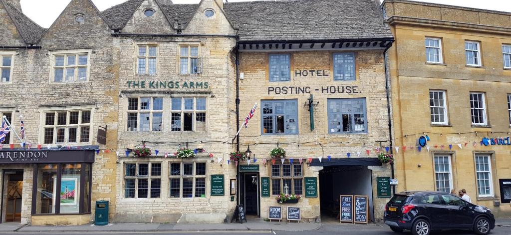 an old brick building with a parking house on a street at The Kings Arms Hotel in Stow on the Wold