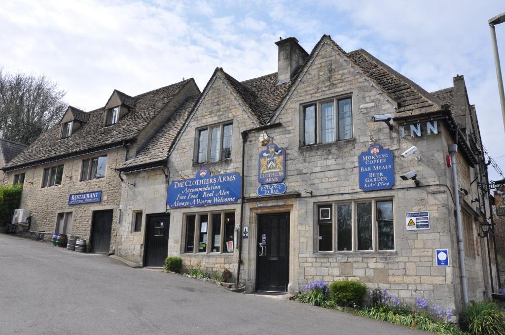 un antiguo edificio de piedra con signos azules. en The Clothiers Arms en Stroud