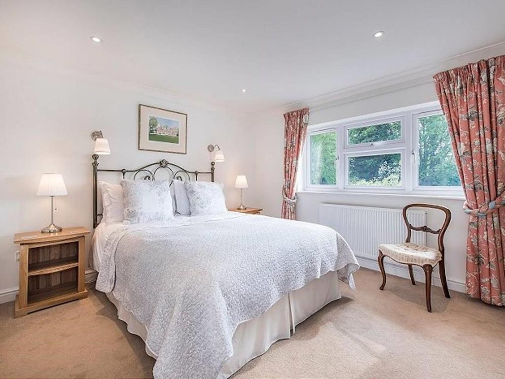 a bedroom with a bed and a chair and two windows at Knole B&B in Sevenoaks