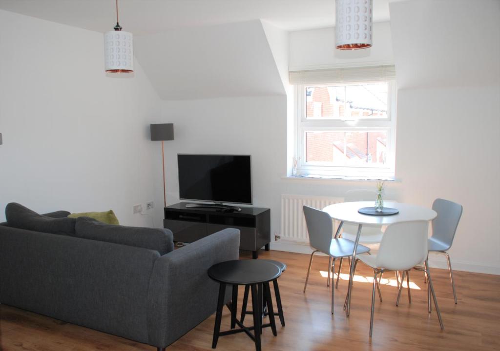 uma sala de estar com um sofá, uma mesa e uma televisão em Coach House em Southampton