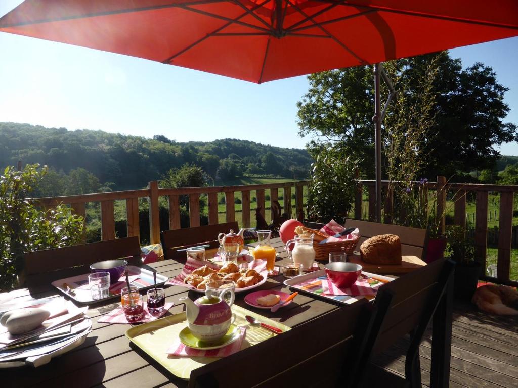 una mesa con comida en una terraza con sombrilla en La Haute Forge B&B, en Thoiré-sur-Dinan