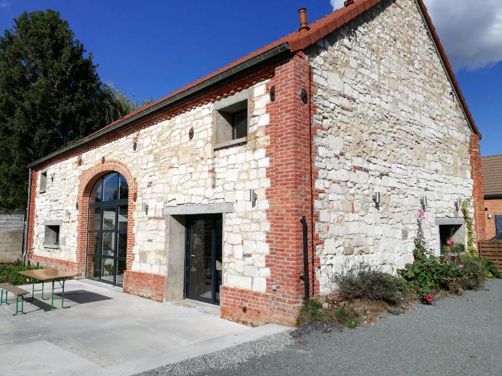 un edificio de ladrillo con una puerta y un banco fuera en La Grange Du Bosquet, en Honnecourt-sur-lʼEscaut