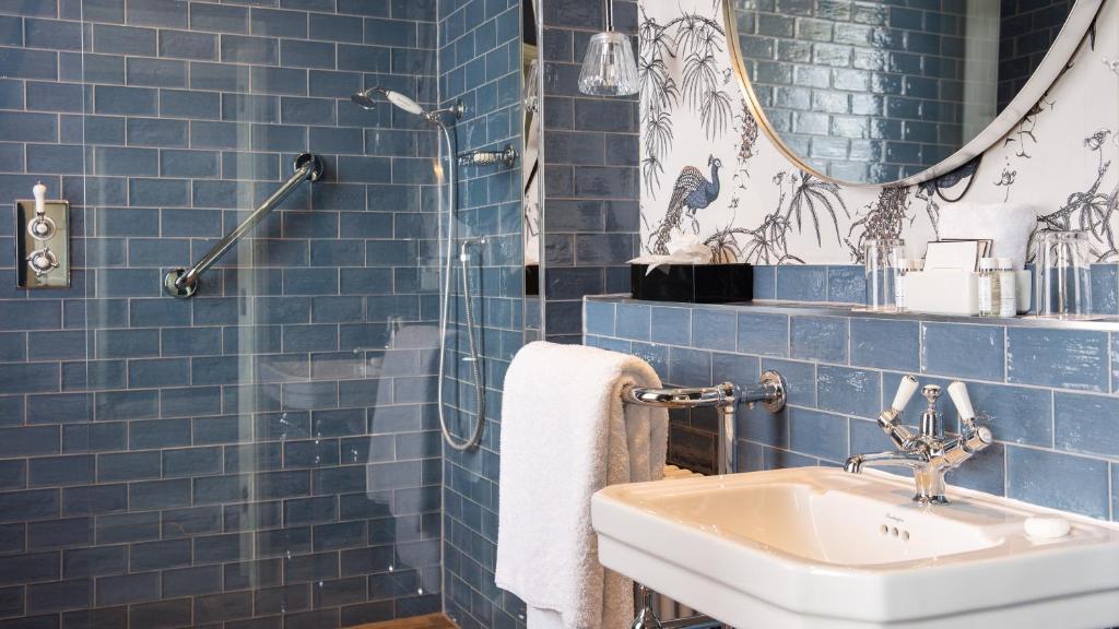 a blue tiled bathroom with a sink and a mirror at The Queensberry Hotel in Bath