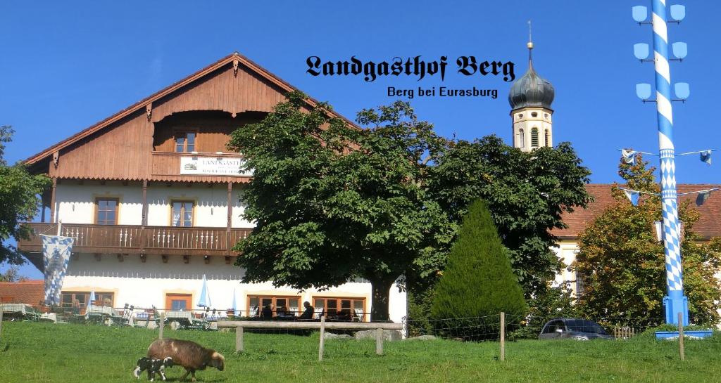 a large building with a tree in front of it at Landgasthof Berg in Eurasburg