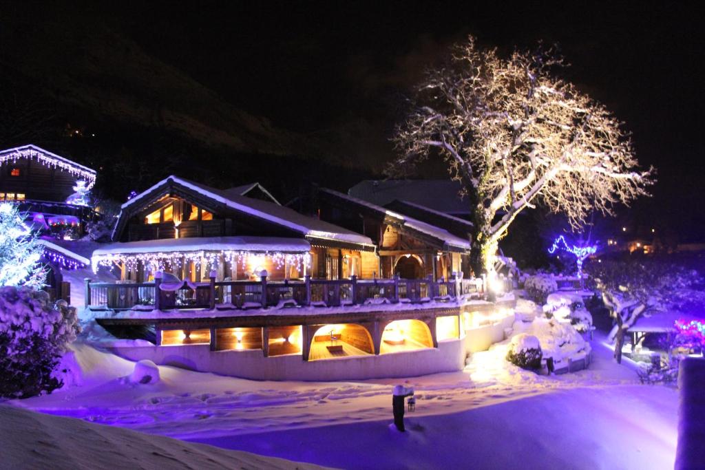 una casa cubierta de nieve por la noche con luces en Chalet de Charme Le Cécla en Passy