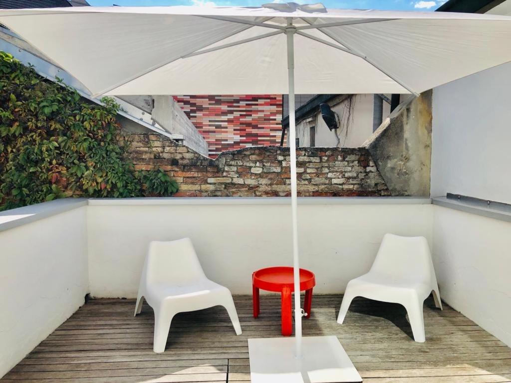 2 weiße Stühle, ein roter Tisch und ein Regenschirm in der Unterkunft Legrenzi Rooms in Mestre