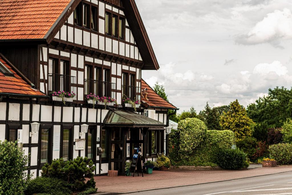 ein schwarzweißes Gebäude mit Blumen an den Fenstern in der Unterkunft Hotel Lingemann in Wallenhorst