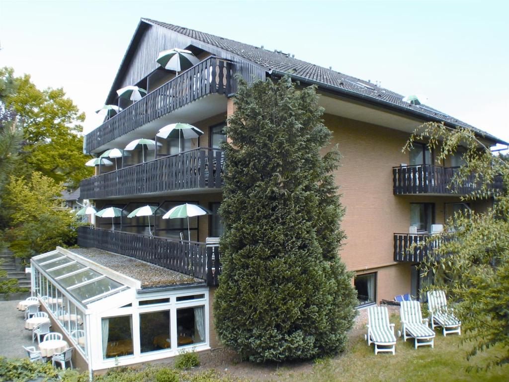 un edificio con sillas y un árbol delante de él en Hotel Pension Marie-Luise, Hotel garni, en Bad Bevensen